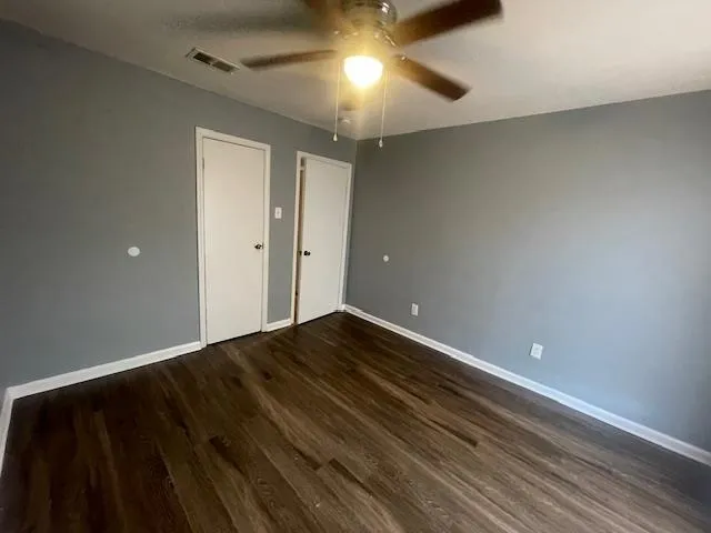 a view of empty room with wooden floor and fan