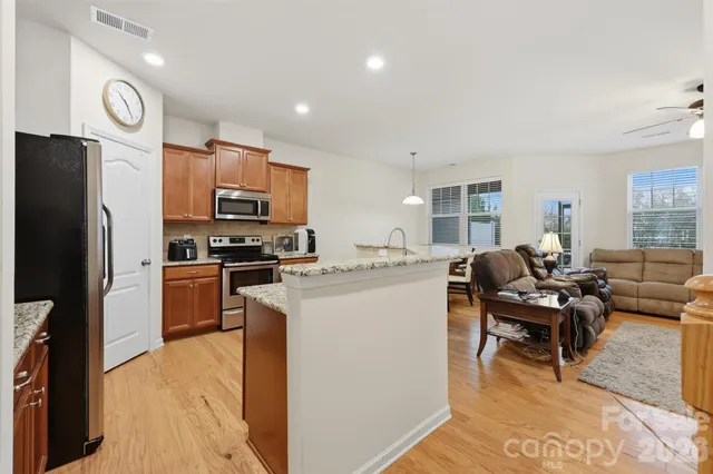 a living room with stainless steel appliances furniture a dining table and kitchen view