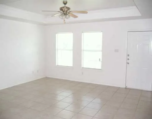 an empty room with windows and fan