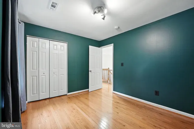 a view of an empty room with wooden floor and windows