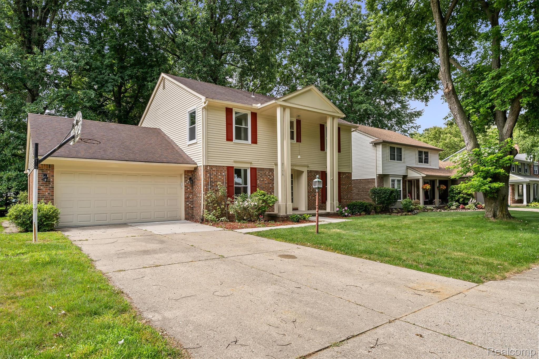 2118 Rutgers Drive Troy, MI 48085 - Photo 2 of 39 Two-story colonial-style residence featuring a prominent portico entrance with substantial columns, brick accents, and a two-car garage