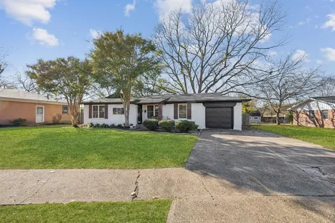 a view of a yard in front of a brick house with a large tree