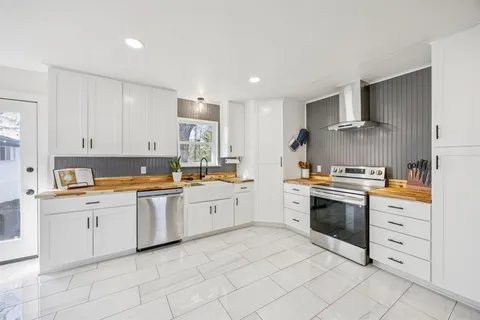 a kitchen with granite countertop white cabinets and white stainless steel appliances