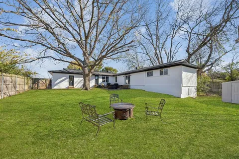 a view of a backyard with table and chairs and large tree