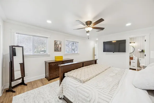 a bedroom with a large bed a flat tv screen and a chandelier