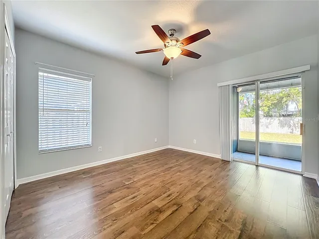 an empty room with wooden floor and ceiling fan