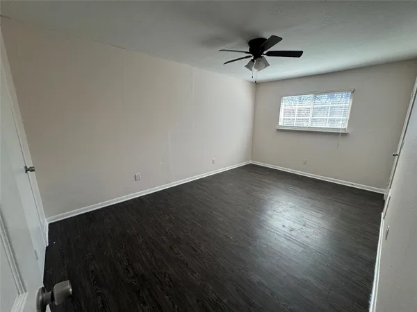 an empty room with wooden floor ceiling fan and windows