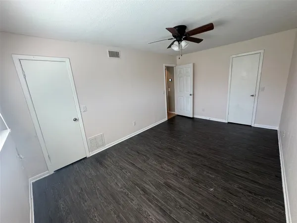 an empty room with wooden floor and ceiling fan