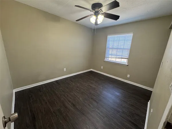 an empty room with wooden floor fan and window