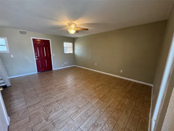 a view of an empty room with window and wooden floor