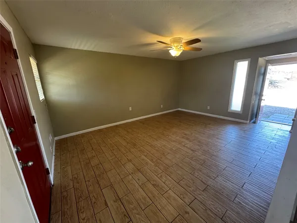 a view of an empty room with wooden floor and a window