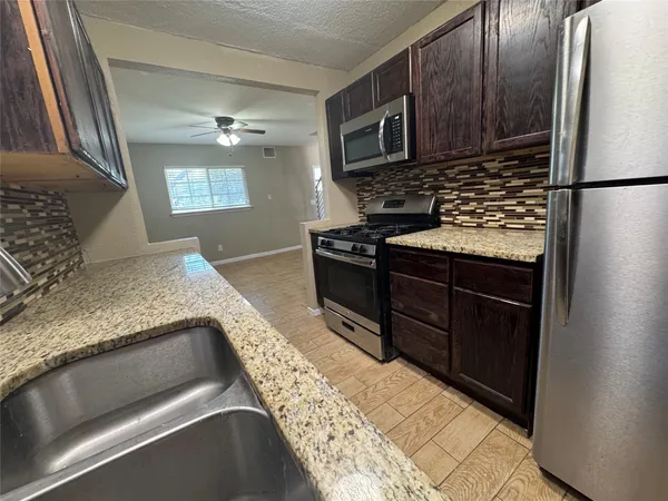 a kitchen with granite countertop a refrigerator stove and microwave