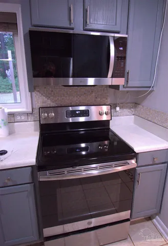 a view of a refrigerator in kitchen and an empty room with wooden floor