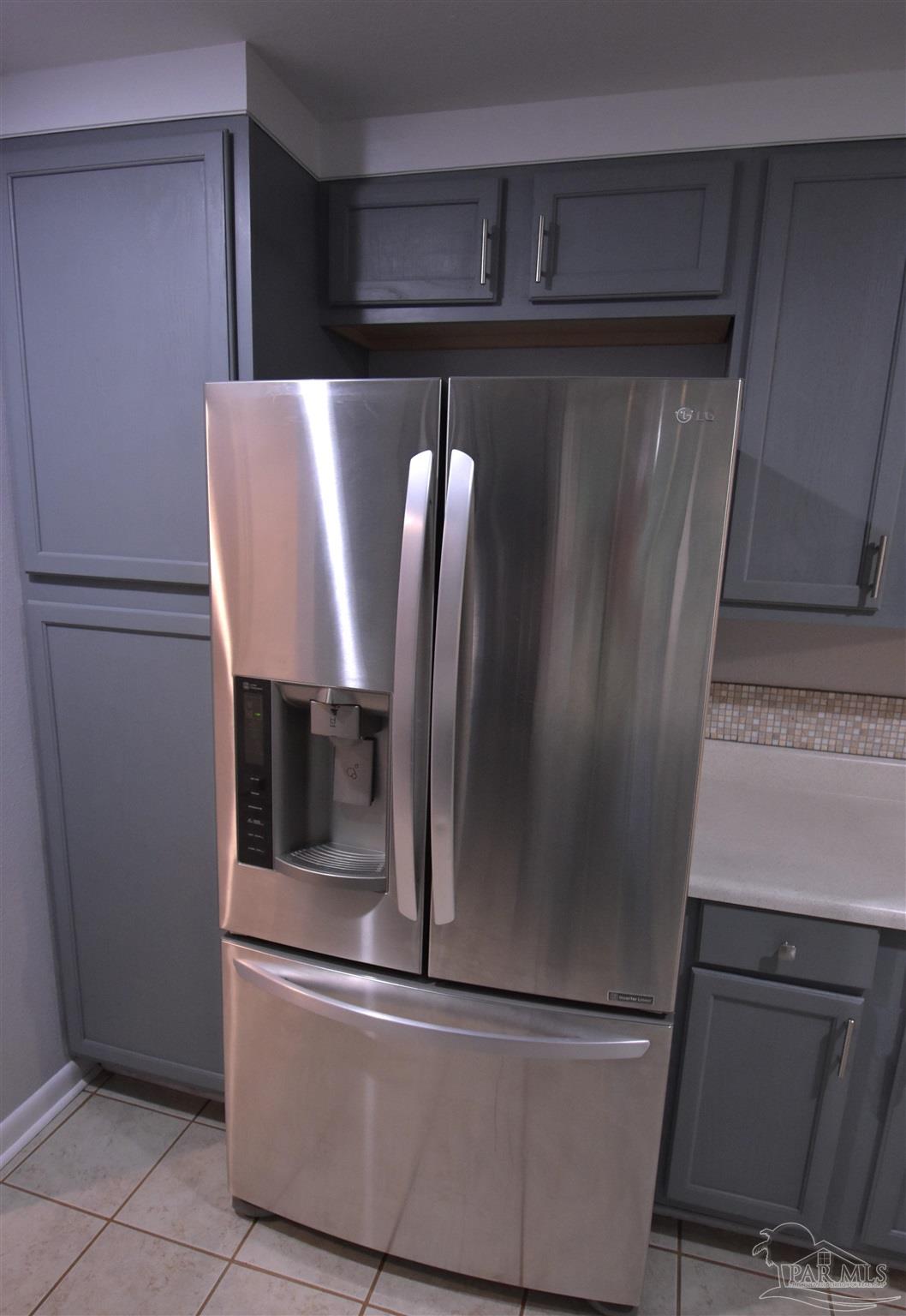 7195 Heath Road Milton, FL 32570 - Photo 25 of 33 a view of a refrigerator in kitchen and an empty room with wooden floor