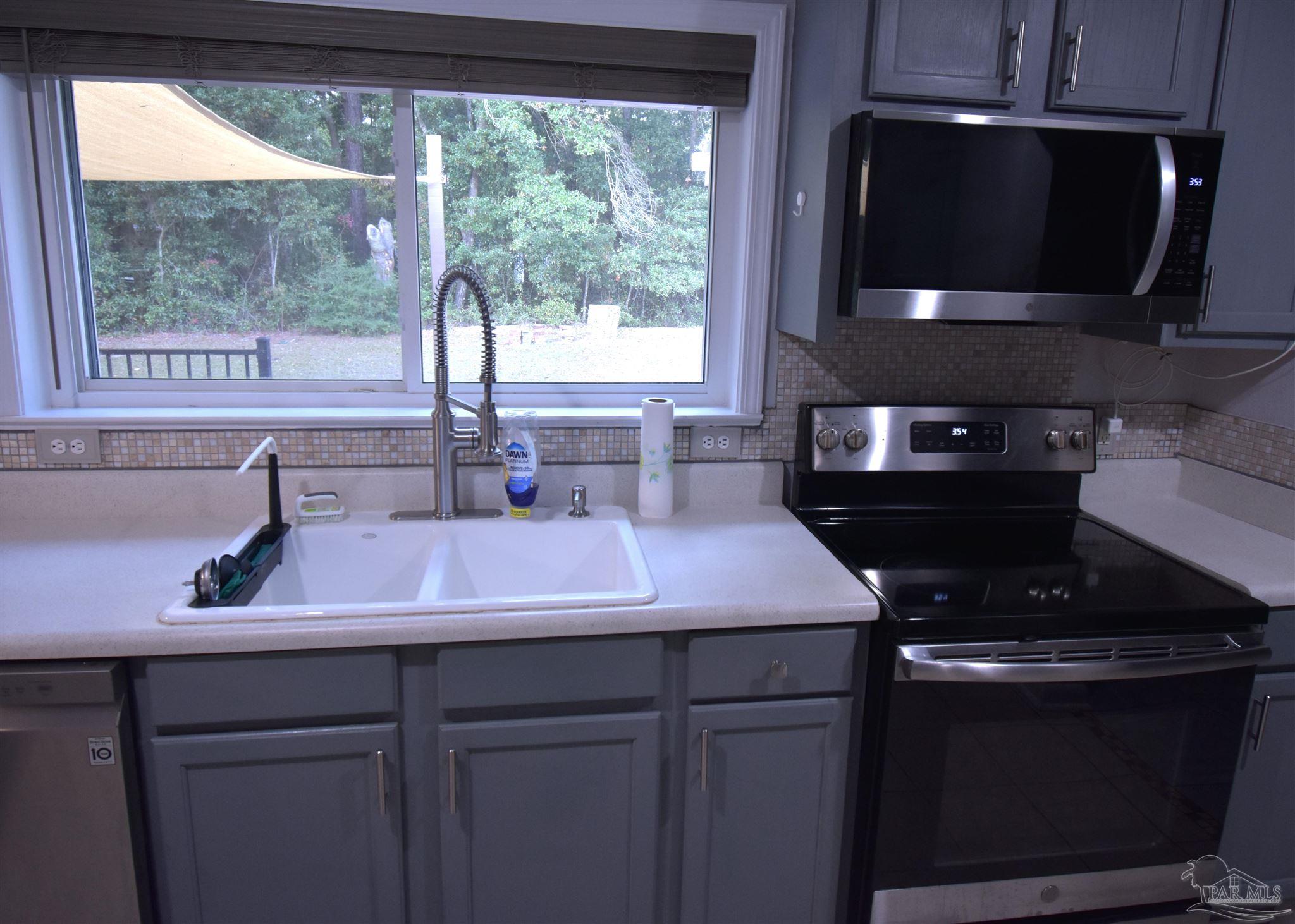 7195 Heath Road Milton, FL 32570 - Photo 26 of 33 a kitchen with a stove a sink and a microwave