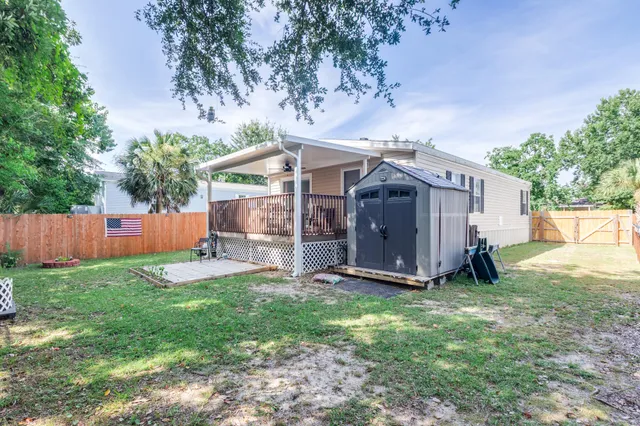 a view of a small house with a big yard and large tree