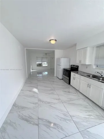 a large white kitchen with cabinets and a refrigerator
