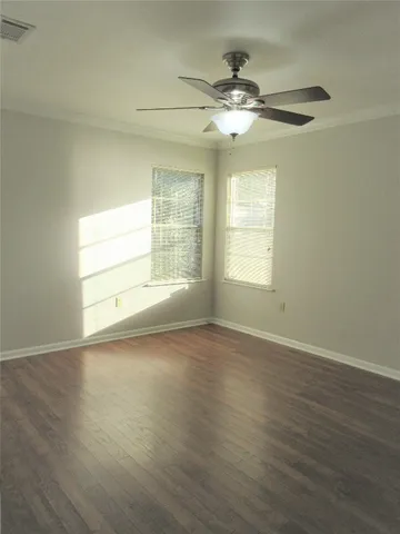 an empty room with wooden floor chandelier fan and windows