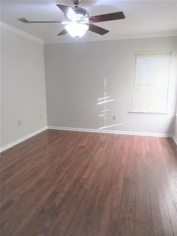 an empty room with wooden floor fan and window