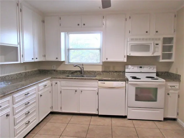 a kitchen with granite countertop white cabinets and white appliances
