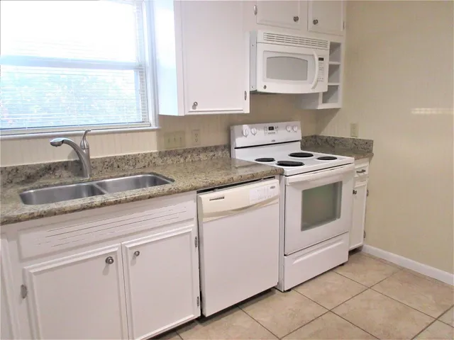 a kitchen with granite countertop white cabinets and white stove