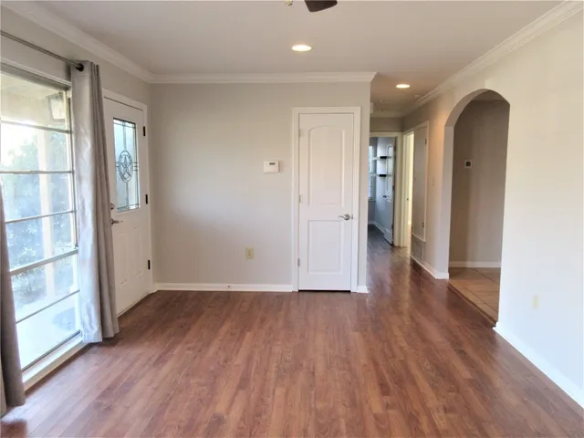 an empty room with wooden floor and windows
