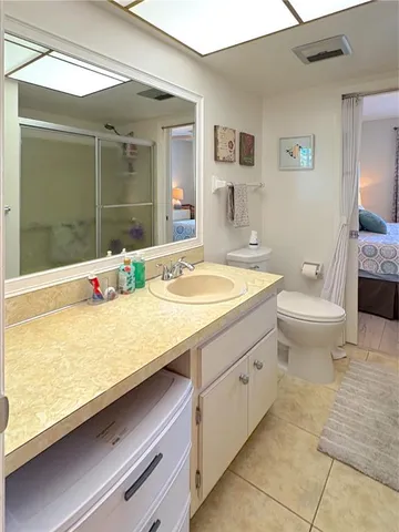 a bathroom with a granite countertop sink a toilet a mirror and shower