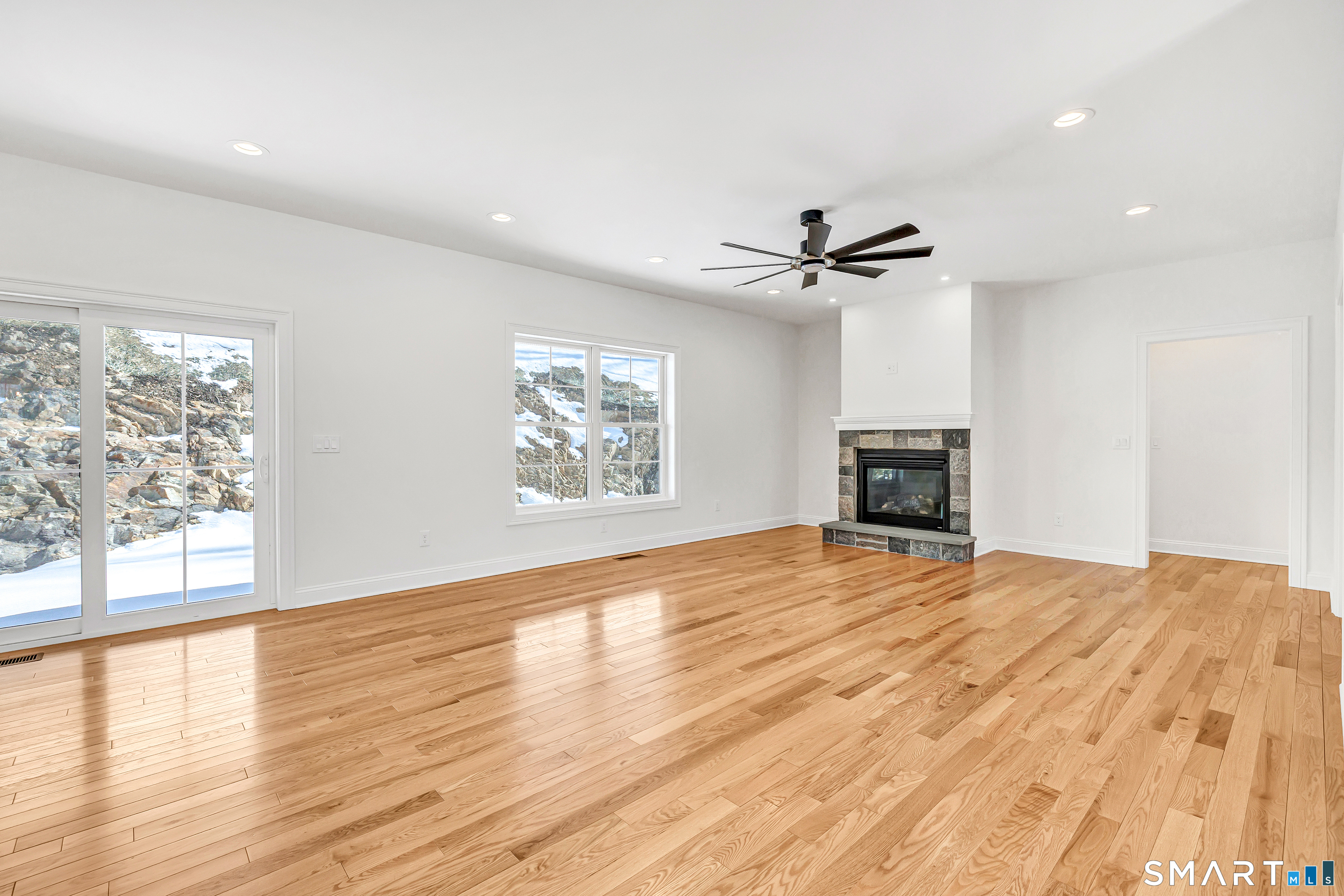 15 Hunting Ridge Road Middlebury, CT 06762 - Photo 4 of 38 an empty room with wooden floor a ceiling fan and windows