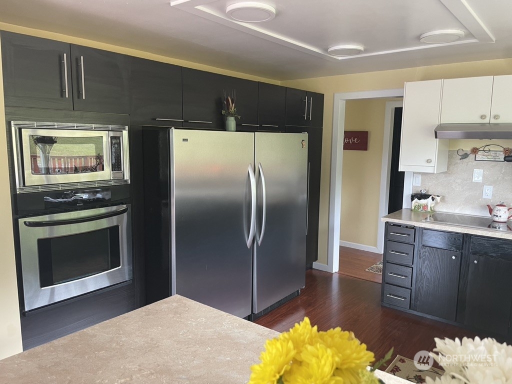 300 Bush Creek Road Elma, WA 98541 - Photo 8 of 21 a kitchen with stainless steel appliances granite countertop a refrigerator a stove and a sink with wooden floors