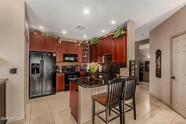 a kitchen with stainless steel appliances kitchen island granite countertop a refrigerator and a stove top oven