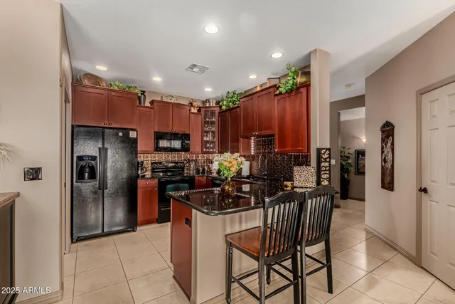 a kitchen with stainless steel appliances kitchen island granite countertop a refrigerator and a stove top oven