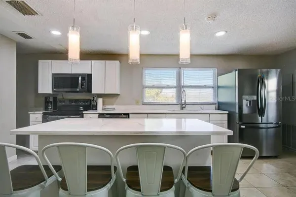 a kitchen with stainless steel appliances kitchen island granite countertop a stove a sink dishwasher a dining table and chairs with wooden floor