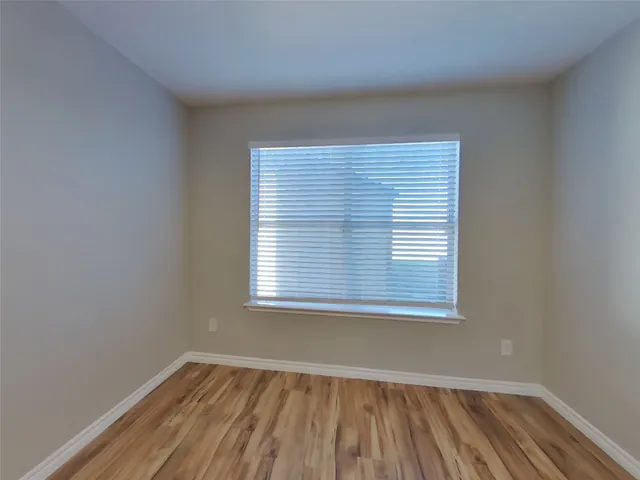 an empty room with wooden floor and a window