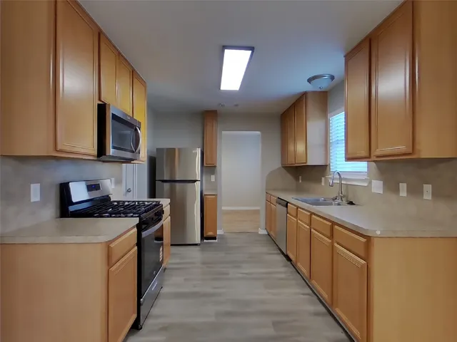 a kitchen with stainless steel appliances granite countertop a stove a sink dishwasher a refrigerator and cabinets with wooden floor