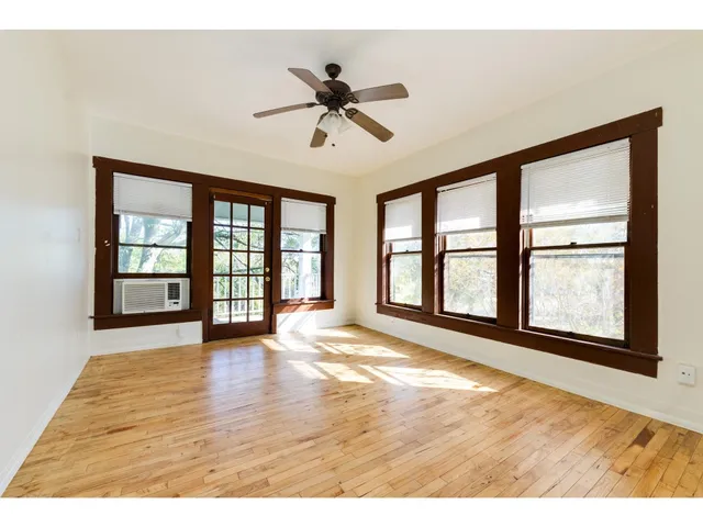 a view of an empty room with a window and wooden floor