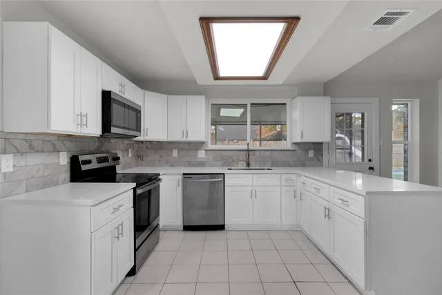 a kitchen with cabinets appliances a sink and a window