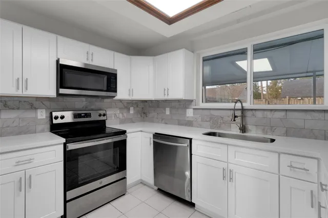 a kitchen with white cabinets stainless steel appliances and sink
