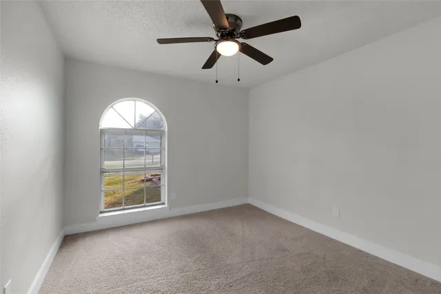 an empty room with windows and ceiling fan