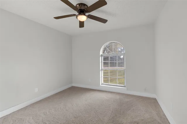 an empty room with windows and ceiling fan