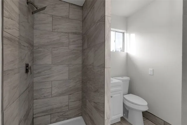 a bathroom with a toilet sink vanity and a window