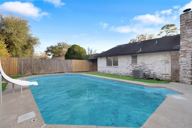 a view of a backyard with large trees and wooden fence