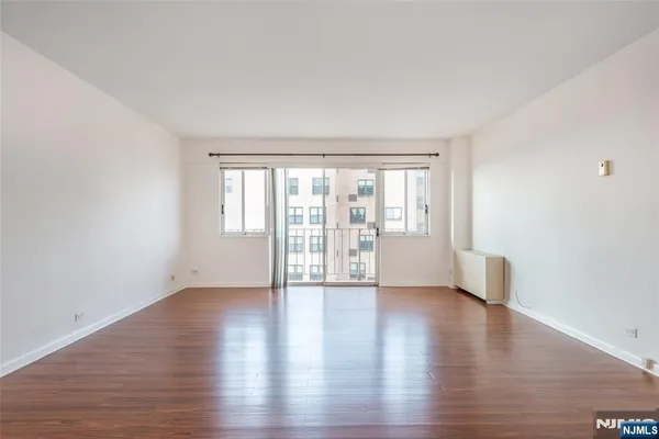 a view of an empty room with a window and wooden floor