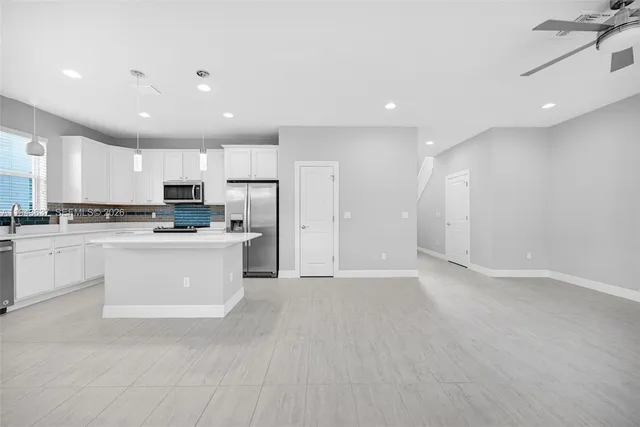 an empty room with a chandelier fan and windows