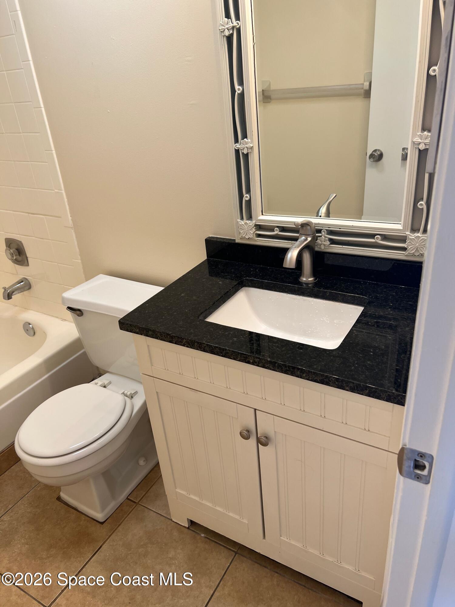 837 Hickory Street, Unit 3 Melbourne, FL 32901 - Photo 6 of 24 a bathroom with a granite countertop toilet sink and mirror