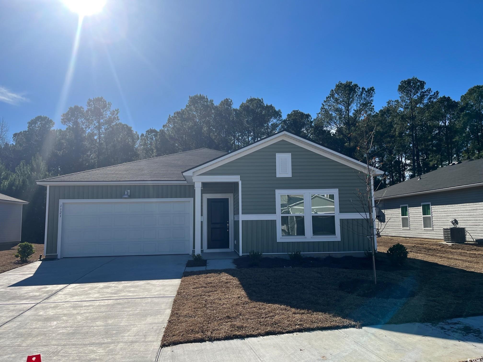 View of front facade with board and batten siding, driveway, and an attached garage