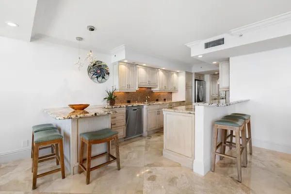 a kitchen with stainless steel appliances granite countertop a refrigerator a sink a stove and oven