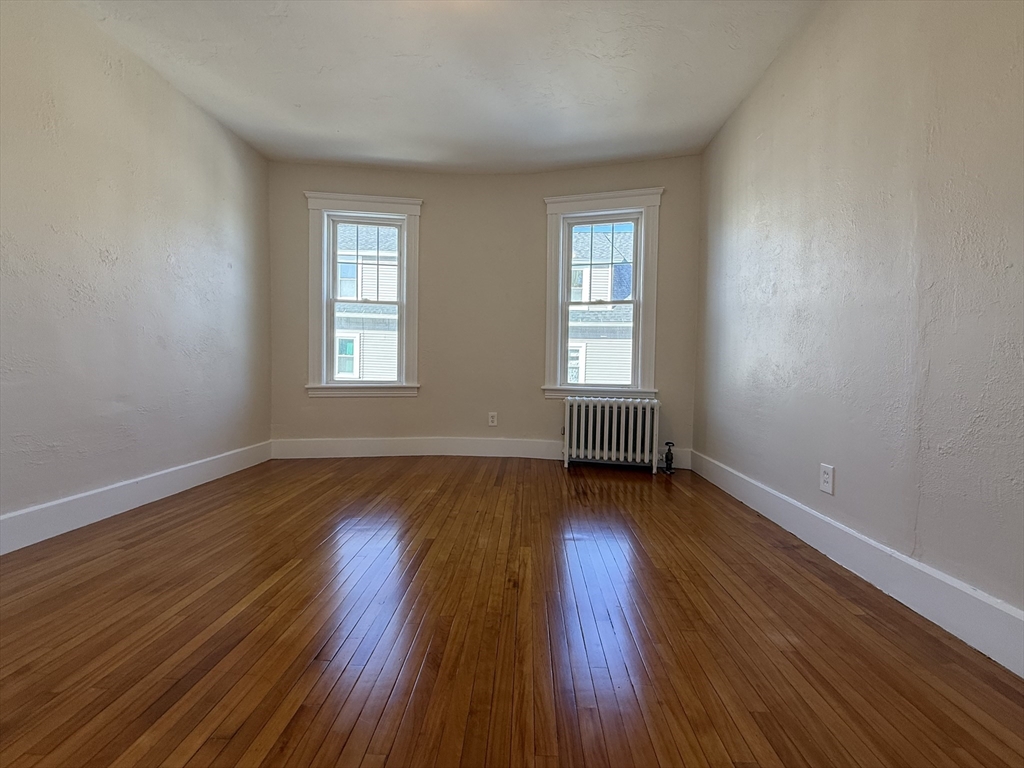304 Lovell Street, Unit 2 Worcester, MA 01602 - Photo 6 of 13 an empty room with wooden floor and windows
