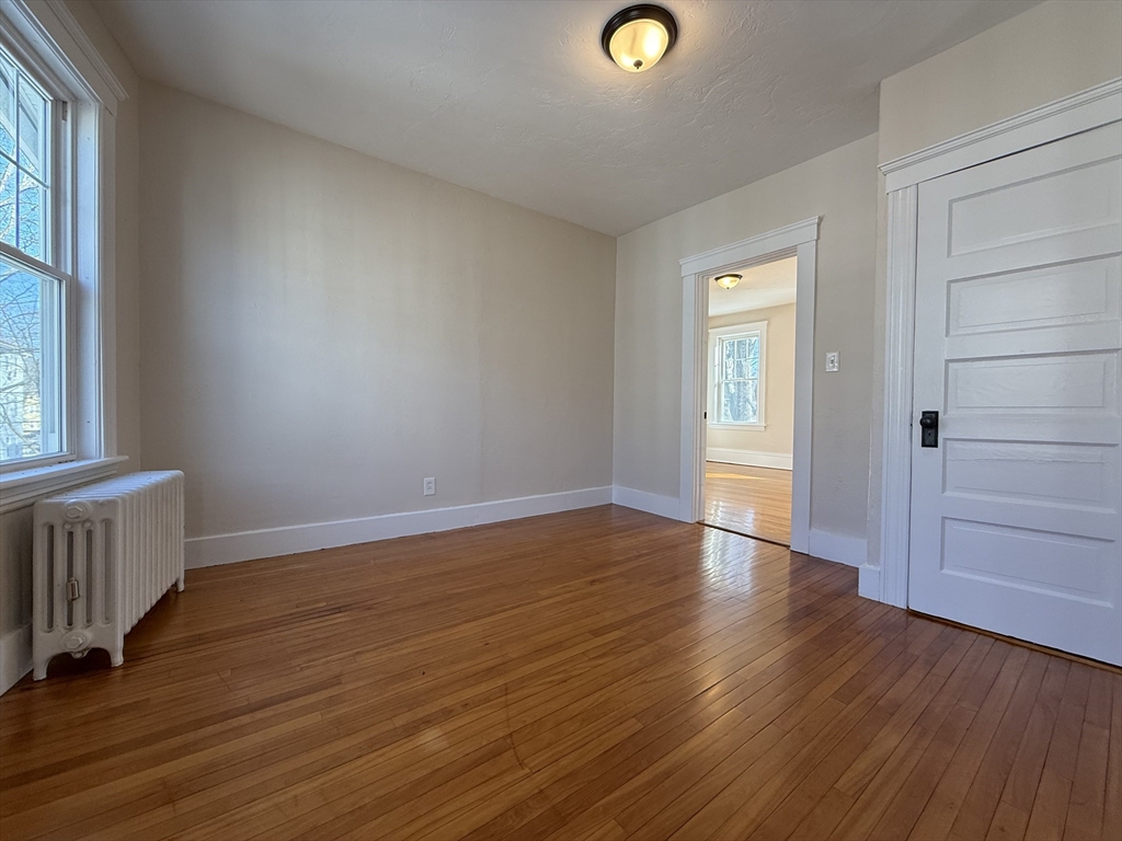 304 Lovell Street, Unit 2 Worcester, MA 01602 - Photo 7 of 13 an empty room with wooden floor and windows