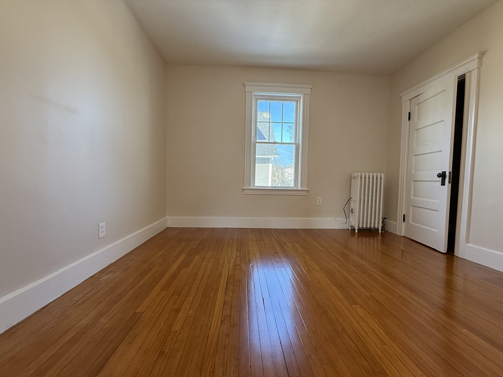 304 Lovell Street, Unit 2 Worcester, MA 01602 - Photo 8 of 13 an empty room with wooden floor and windows