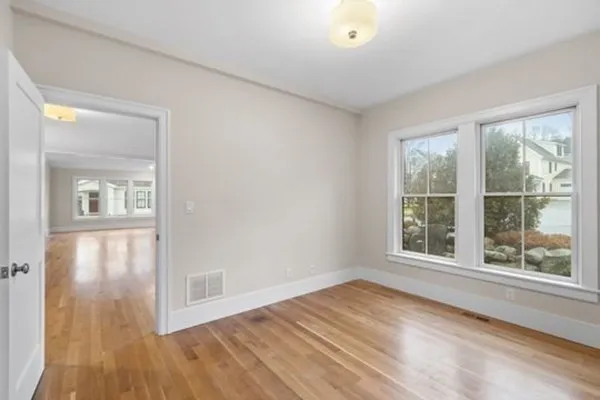 a view of empty room with wooden floor and fan